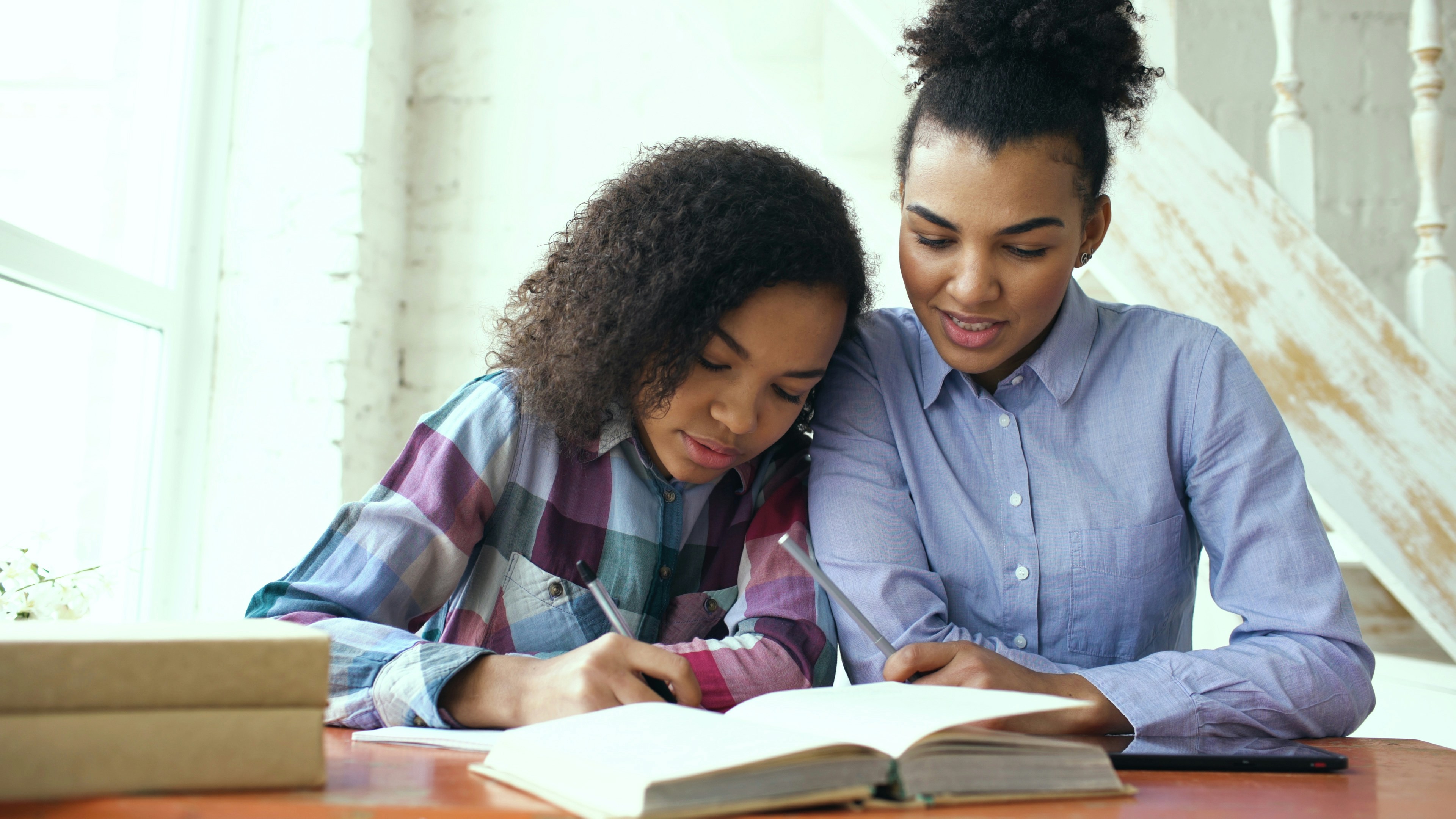 Parent and teen working through homework together at a table